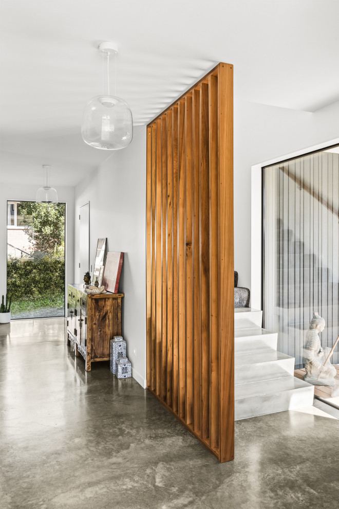 Inspiration pour une grande porte d'entrée design avec un mur blanc, sol en béton ciré, une porte en bois foncé et un sol gris.