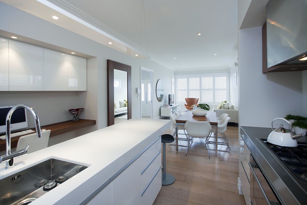 This is an example of a contemporary open plan kitchen in Auckland with an undermount sink, flat-panel cabinets and white cabinets.