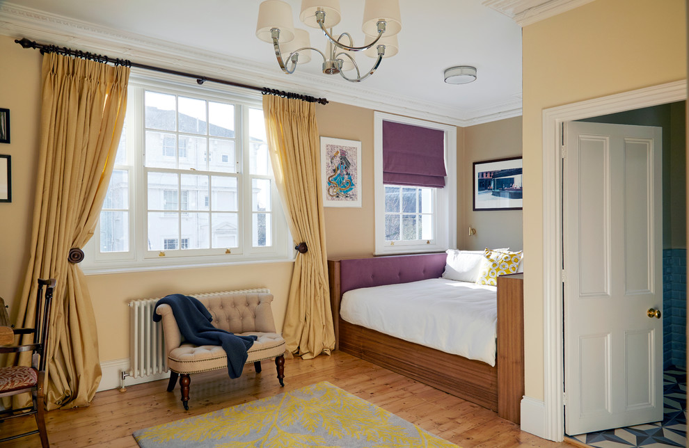 Design ideas for a transitional master bedroom in London with yellow walls and light hardwood floors.