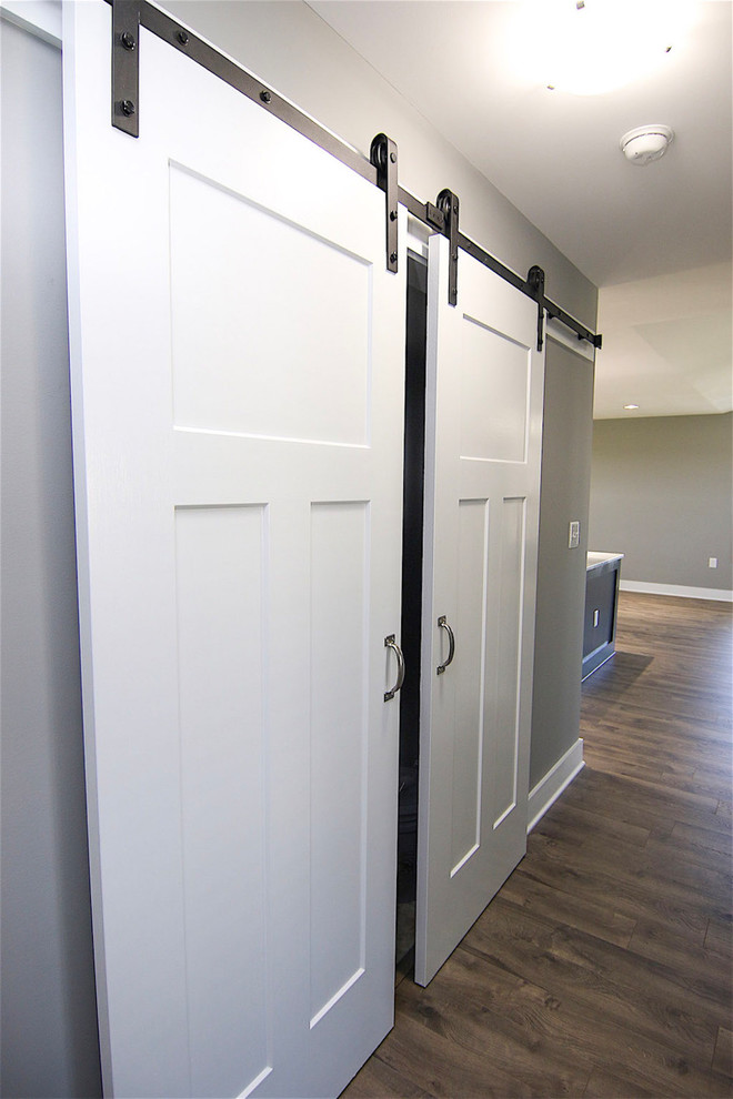This is an example of a small arts and crafts single-wall laundry cupboard in Raleigh with grey walls, vinyl floors, a side-by-side washer and dryer and grey floor.
