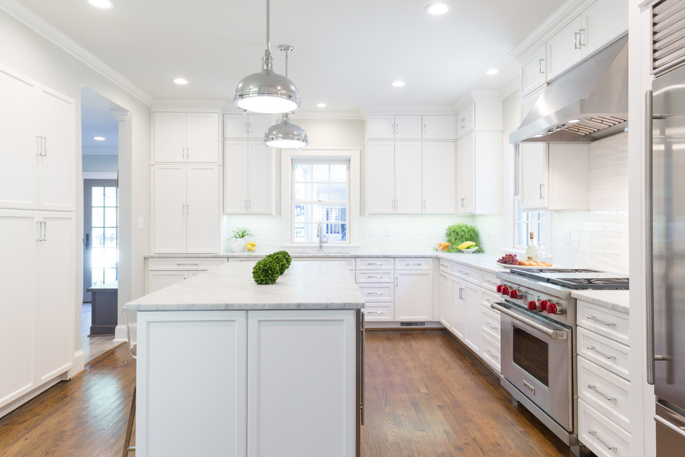 Large transitional l-shaped separate kitchen in Charlotte with an undermount sink, flat-panel cabinets, white cabinets, marble benchtops, white splashback, ceramic splashback, stainless steel appliances, light hardwood floors and with island.