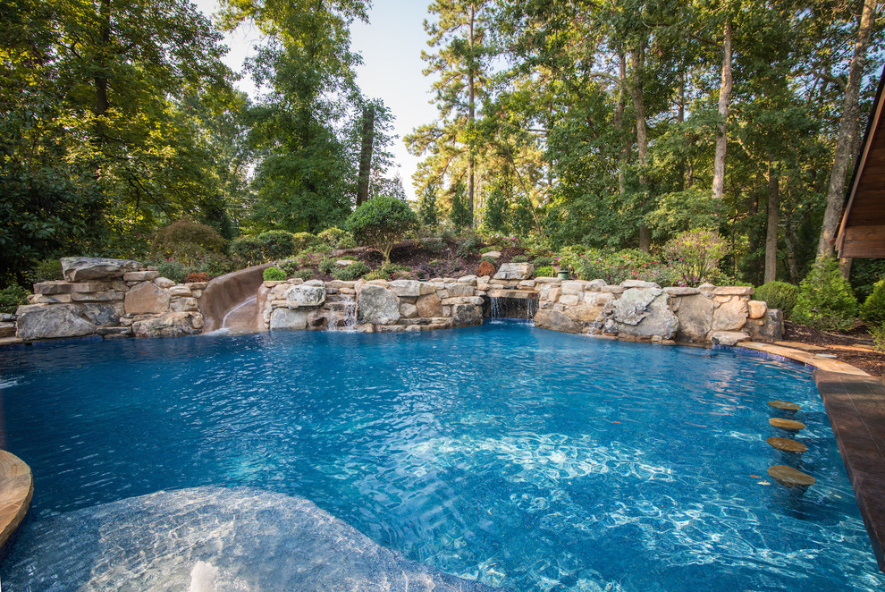 Inspiration for a tropical backyard custom-shaped natural pool in Atlanta with a water slide and concrete pavers.