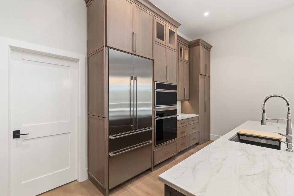 Inspiration for a large transitional galley light wood floor and brown floor eat-in kitchen remodel in Tampa with a double-bowl sink, shaker cabinets, dark wood cabinets, quartz countertops, gray backsplash, stone slab backsplash, stainless steel appliances, an island and gray countertops