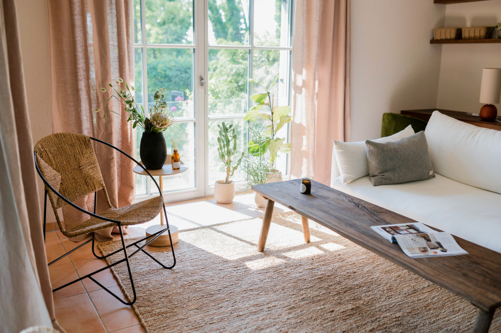 Imagen de sala de estar abierta mediterránea de tamaño medio con paredes beige, suelo de baldosas de terracota, estufa de leña y suelo naranja