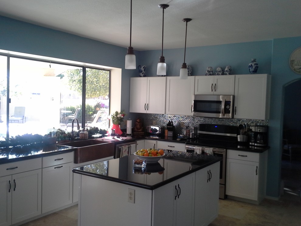Inspiration for a mid-sized transitional l-shaped ceramic tile and beige floor kitchen remodel in Phoenix with a farmhouse sink, shaker cabinets, white cabinets, laminate countertops, metallic backsplash, metal backsplash, stainless steel appliances and an island