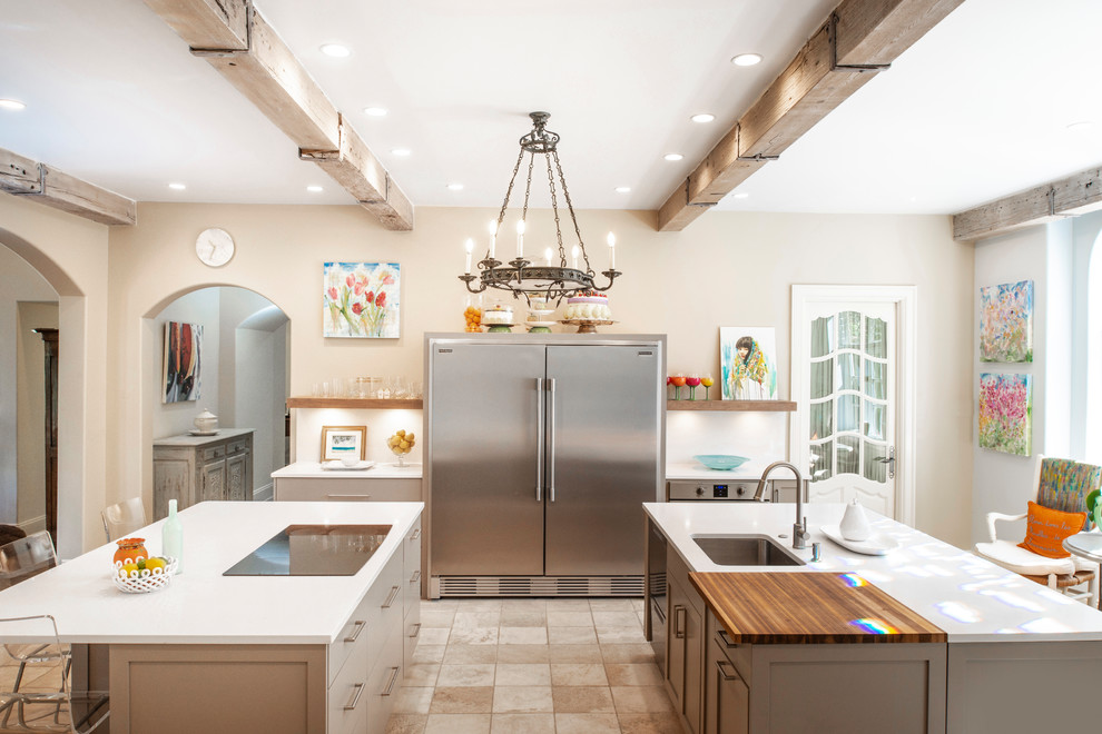 Example of a mid-sized transitional ceramic tile and brown floor enclosed kitchen design with an undermount sink, flat-panel cabinets, beige cabinets, quartzite countertops, white backsplash, ceramic backsplash, stainless steel appliances, two islands and white countertops