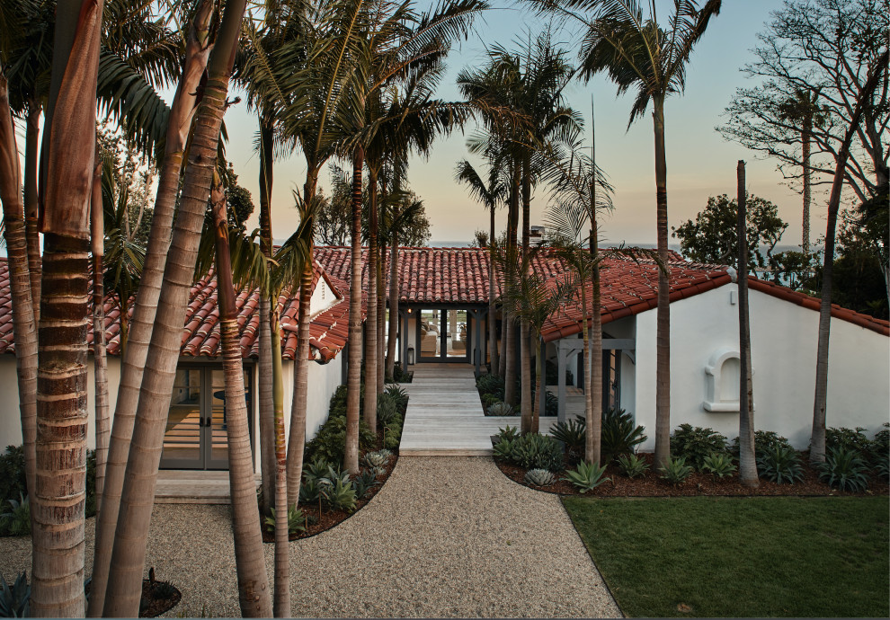 Large mediterranean one-storey adobe white house exterior in Los Angeles with a gable roof, a tile roof and a red roof.