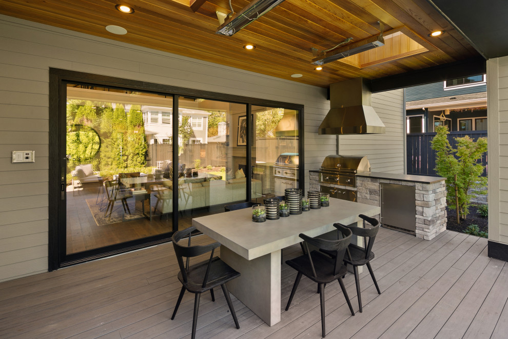 Photo of a large country backyard deck in Seattle with an outdoor kitchen and a roof extension.