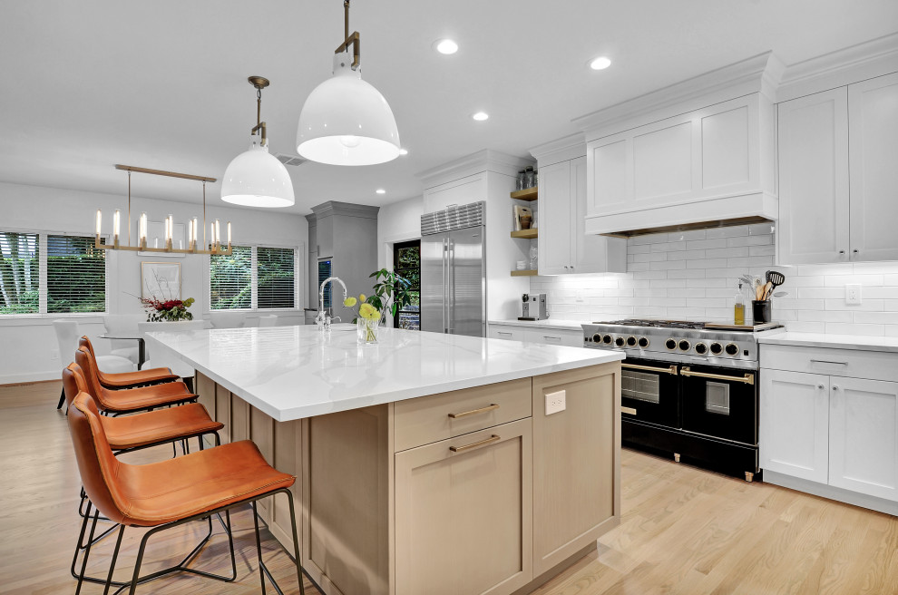 Kitchen - transitional light wood floor and beige floor kitchen idea in Seattle with shaker cabinets, white cabinets, white backsplash, subway tile backsplash, black appliances, an island and white countertops