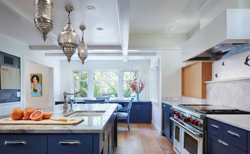 Large eclectic u-shaped kitchen pantry in Minneapolis with an undermount sink, flat-panel cabinets, blue cabinets, marble benchtops, white splashback, stone slab splashback, stainless steel appliances, light hardwood floors and with island.