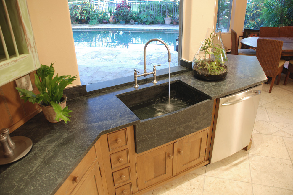 Enclosed kitchen - large rustic u-shaped ceramic tile and beige floor enclosed kitchen idea in Miami with a farmhouse sink, beaded inset cabinets, green cabinets, solid surface countertops, brown backsplash, wood backsplash, stainless steel appliances and an island