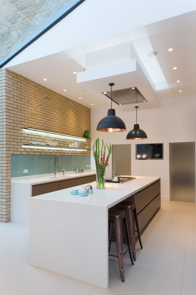 Inspiration for a large contemporary galley eat-in kitchen in London with an integrated sink, flat-panel cabinets, medium wood cabinets, solid surface benchtops, glass sheet splashback, panelled appliances, ceramic floors and with island.