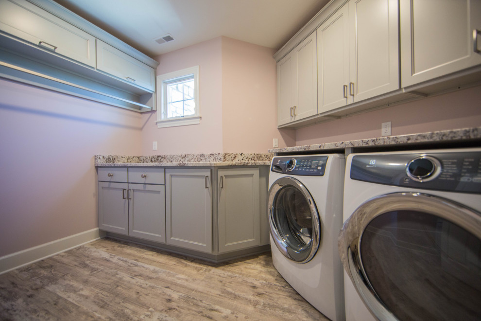 Large classic separated utility room in Indianapolis with recessed-panel cabinets, grey cabinets, beige walls, medium hardwood flooring, a side by side washer and dryer, brown floors and multicoloured worktops.