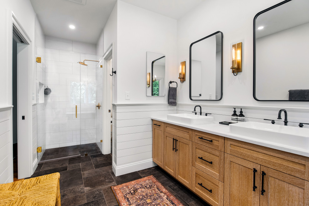 Photo of an industrial master bathroom in Other with light wood cabinets, a niche, a double vanity, planked wall panelling, a freestanding tub, a curbless shower, a two-piece toilet, white tile, porcelain tile, white walls, porcelain floors, a vessel sink, engineered quartz benchtops, black floor, a hinged shower door, white benchtops, a built-in vanity and shaker cabinets.