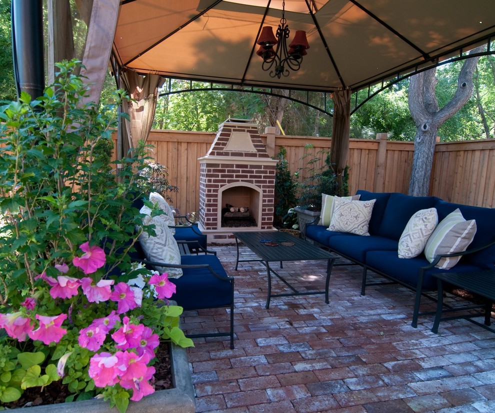Mid-sized transitional backyard patio in Denver with a water feature, brick pavers and an awning.