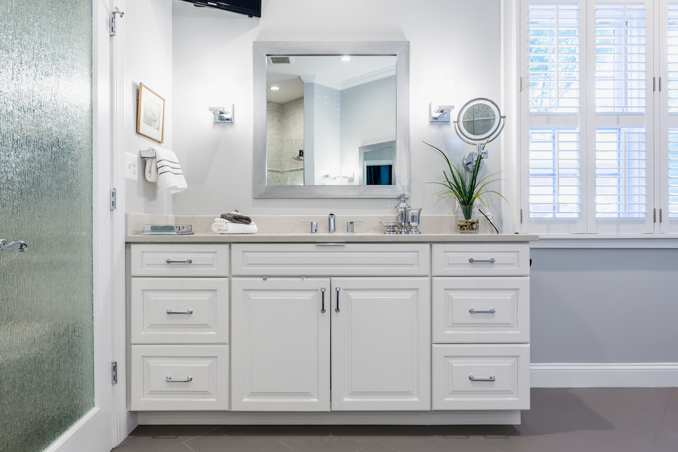 Design ideas for a large traditional master bathroom in DC Metro with raised-panel cabinets, white cabinets, a corner shower, a one-piece toilet, gray tile, grey walls, an undermount sink, grey floor, a hinged shower door, marble, porcelain floors, marble benchtops and white benchtops.