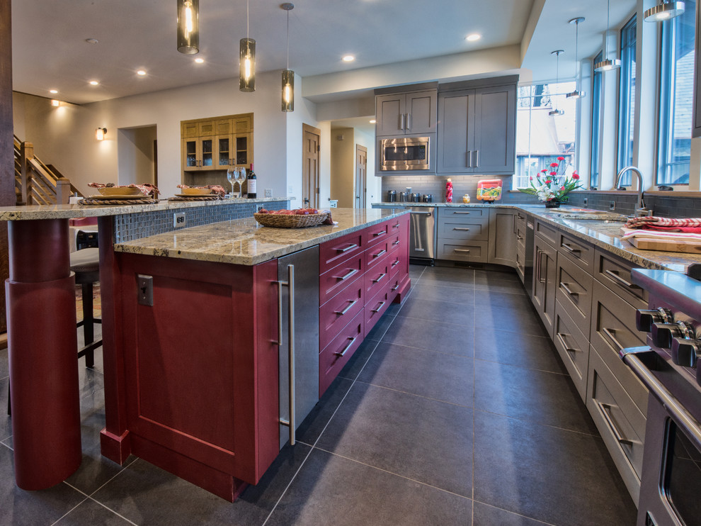 Large transitional u-shaped limestone floor eat-in kitchen photo with an undermount sink, shaker cabinets, gray cabinets, granite countertops, gray backsplash, glass tile backsplash, stainless steel appliances and an island
