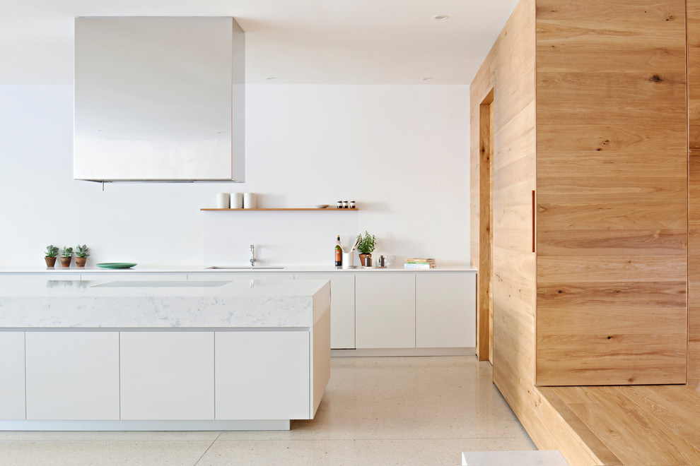 Design ideas for a large contemporary galley kitchen in Melbourne with an undermount sink, marble benchtops, white splashback, stone tile splashback, concrete floors, with island, white floor, white benchtop, flat-panel cabinets and white cabinets.