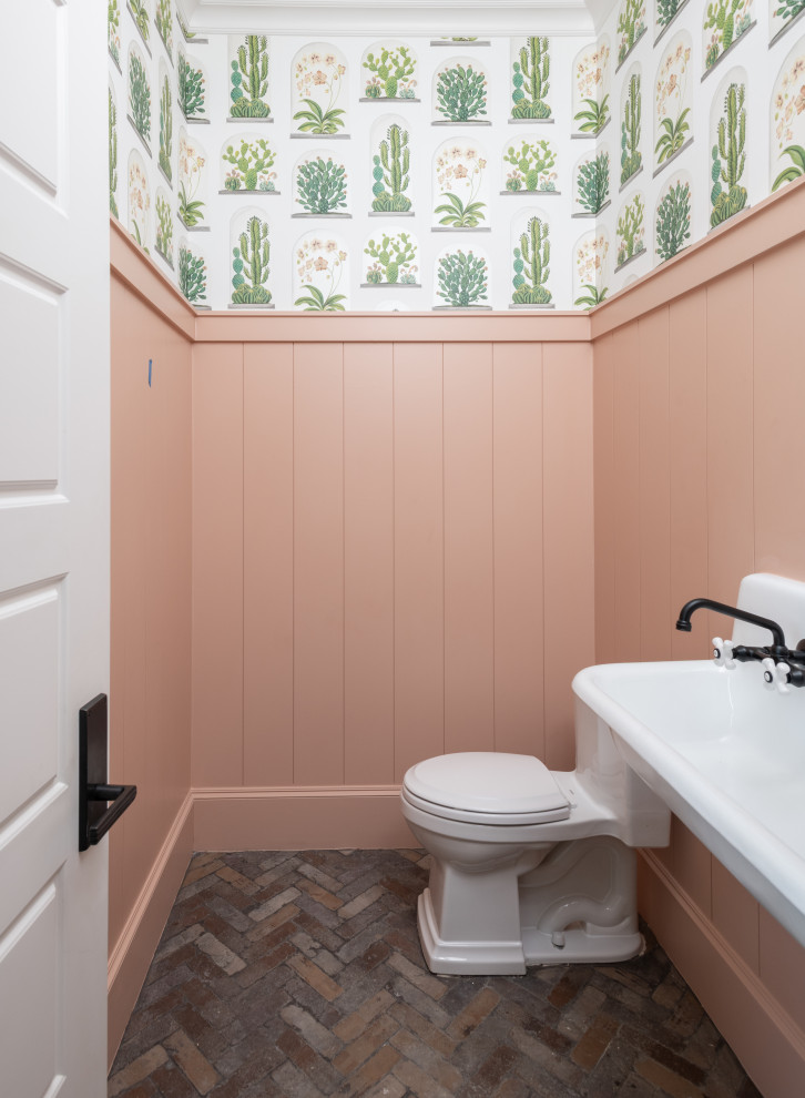 Mid-sized farmhouse brick floor, brown floor and wallpaper powder room photo in Dallas with white cabinets, pink walls, a trough sink and a floating vanity