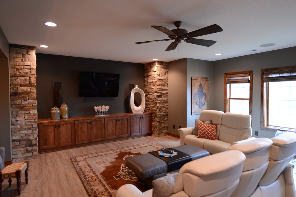 Example of a large transitional walk-out light wood floor basement design with gray walls, a two-sided fireplace and a stone fireplace