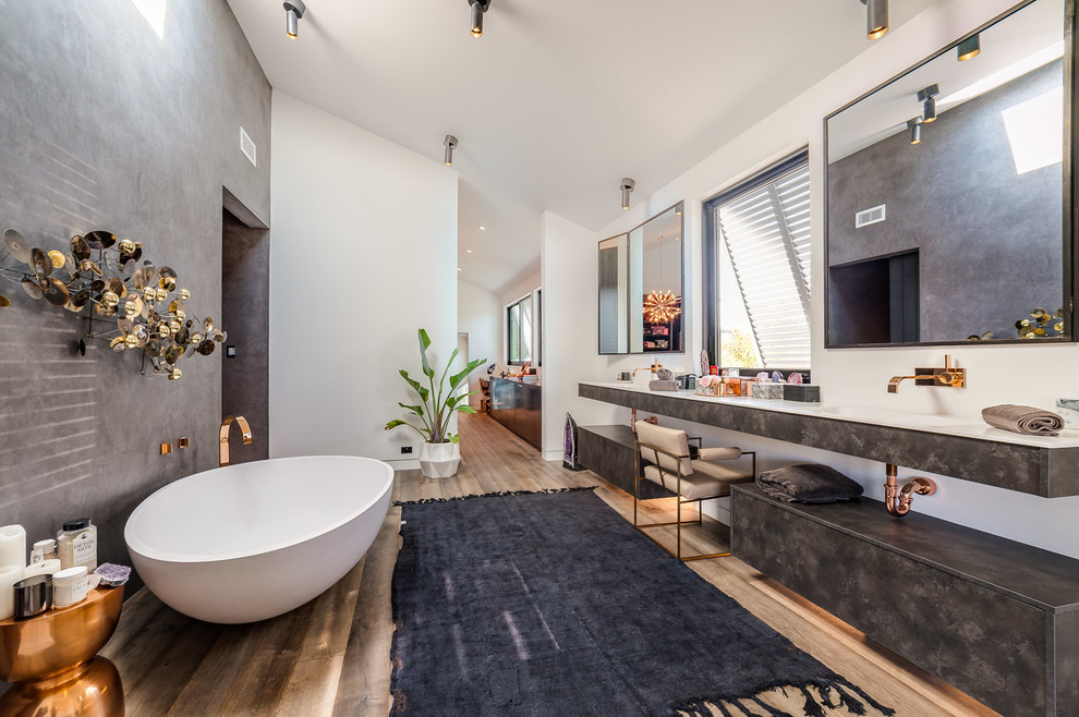 Large contemporary master wet room bathroom in Los Angeles with a freestanding tub, white walls, an integrated sink, a one-piece toilet, solid surface benchtops, an open shower and medium hardwood floors.