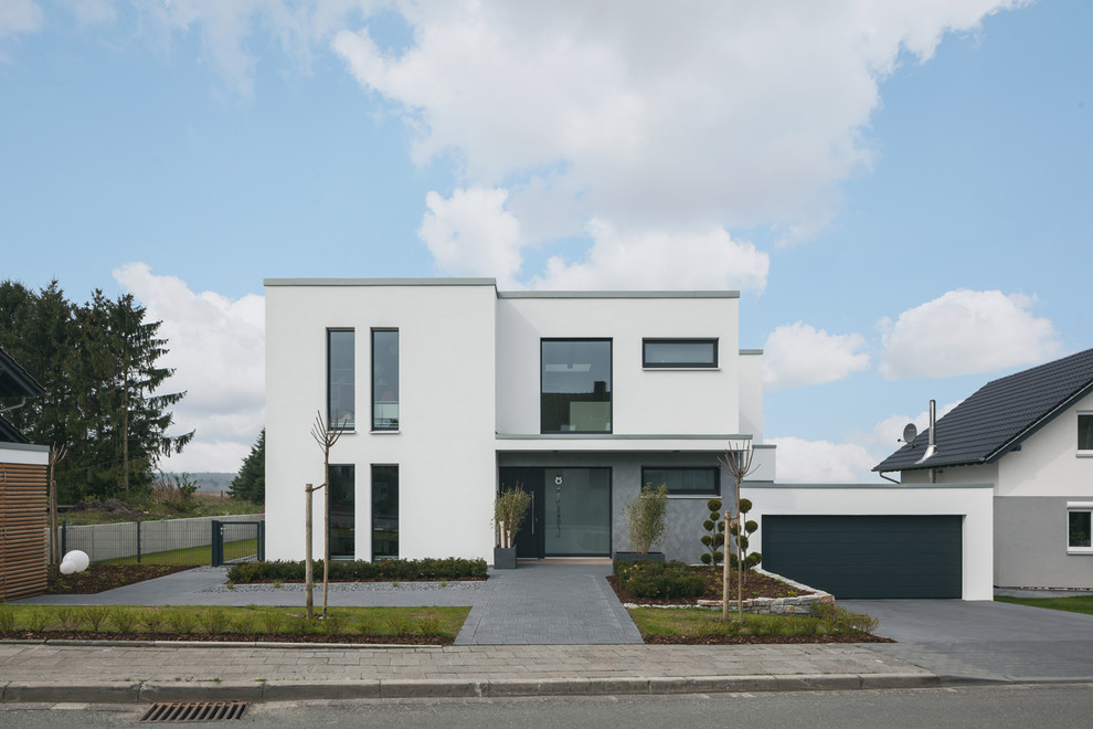 Design ideas for a mid-sized contemporary two-storey stucco white house exterior in Dortmund with a flat roof.