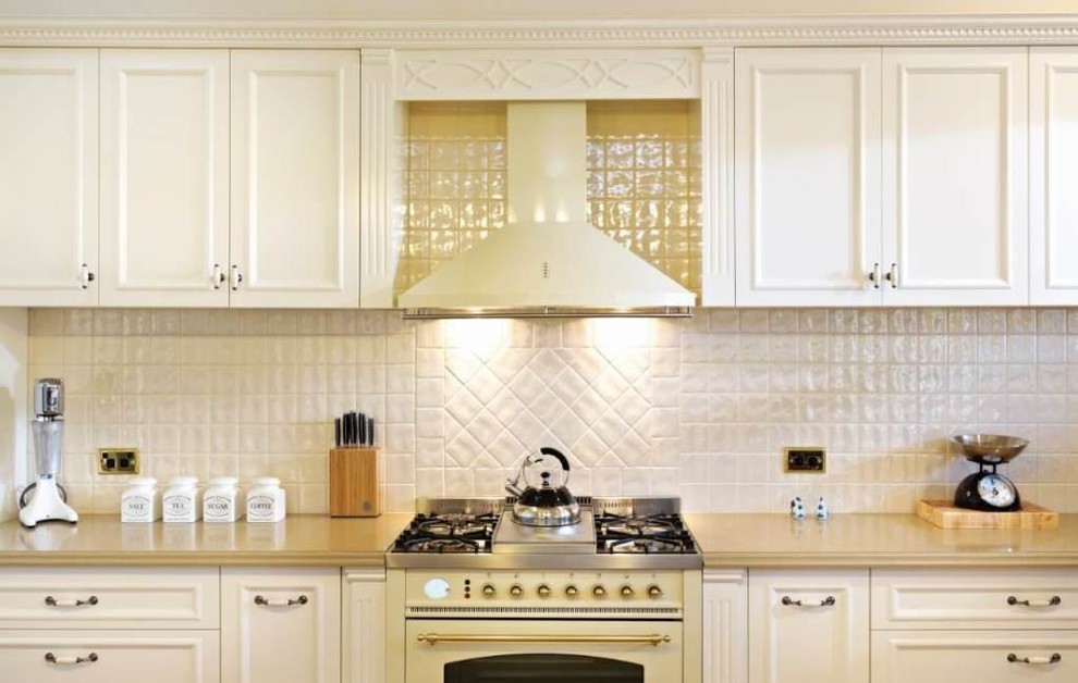 Photo of a country l-shaped eat-in kitchen in Melbourne with an undermount sink, shaker cabinets, white cabinets, soapstone benchtops, white splashback, porcelain splashback and white appliances.