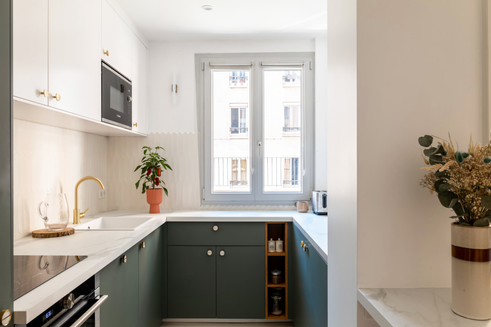 Photo of a mid-sized contemporary u-shaped kitchen in Paris with a single-bowl sink, laminate benchtops, white splashback, matchstick tile splashback, black appliances, concrete floors, beige floor and white benchtop.