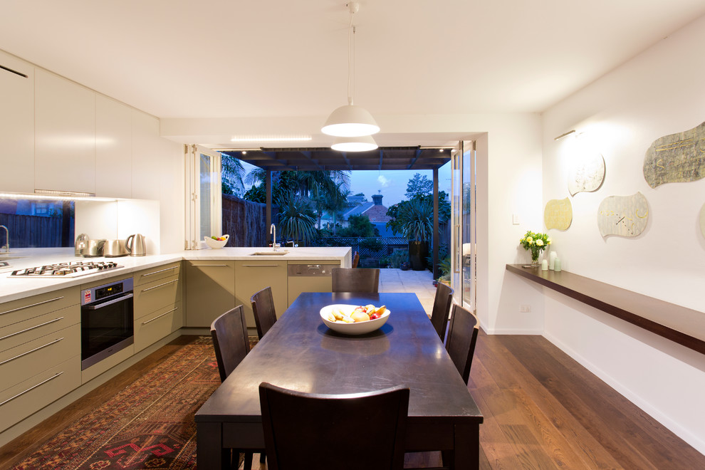 Design ideas for a contemporary kitchen in Sydney with flat-panel cabinets, green cabinets, metallic splashback, glass sheet splashback and stainless steel appliances.