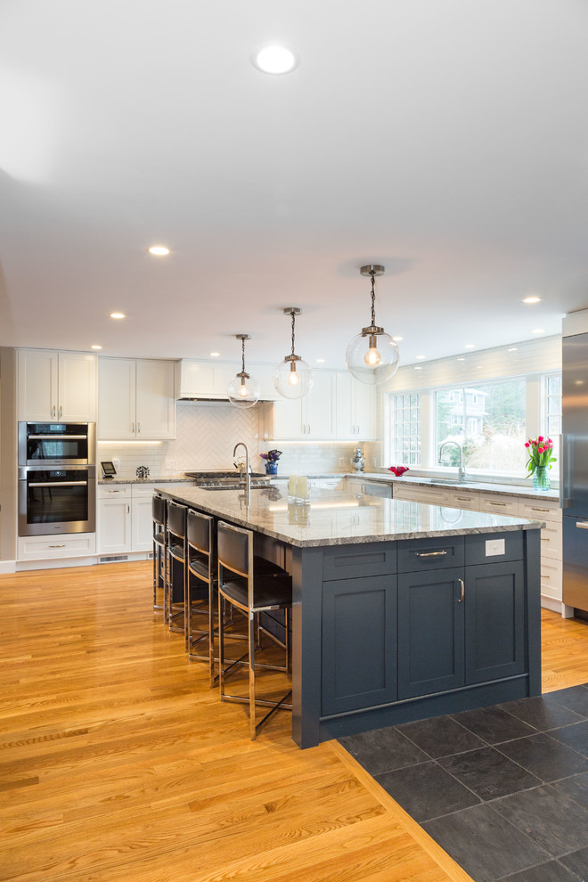 Photo of a large transitional l-shaped kitchen in Boston with an undermount sink, shaker cabinets, white cabinets, granite benchtops, white splashback, subway tile splashback, stainless steel appliances, medium hardwood floors, with island and brown floor.