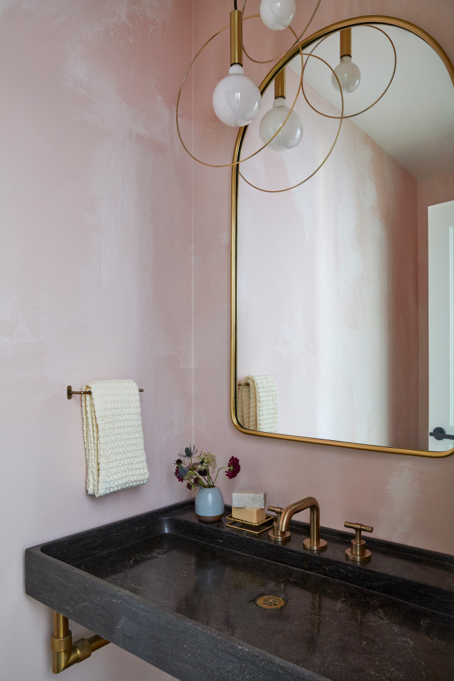Modelo de aseo flotante escandinavo pequeño con puertas de armario negras, paredes rosas, suelo de pizarra, lavabo suspendido, encimera de piedra caliza, suelo gris, encimeras negras y papel pintado