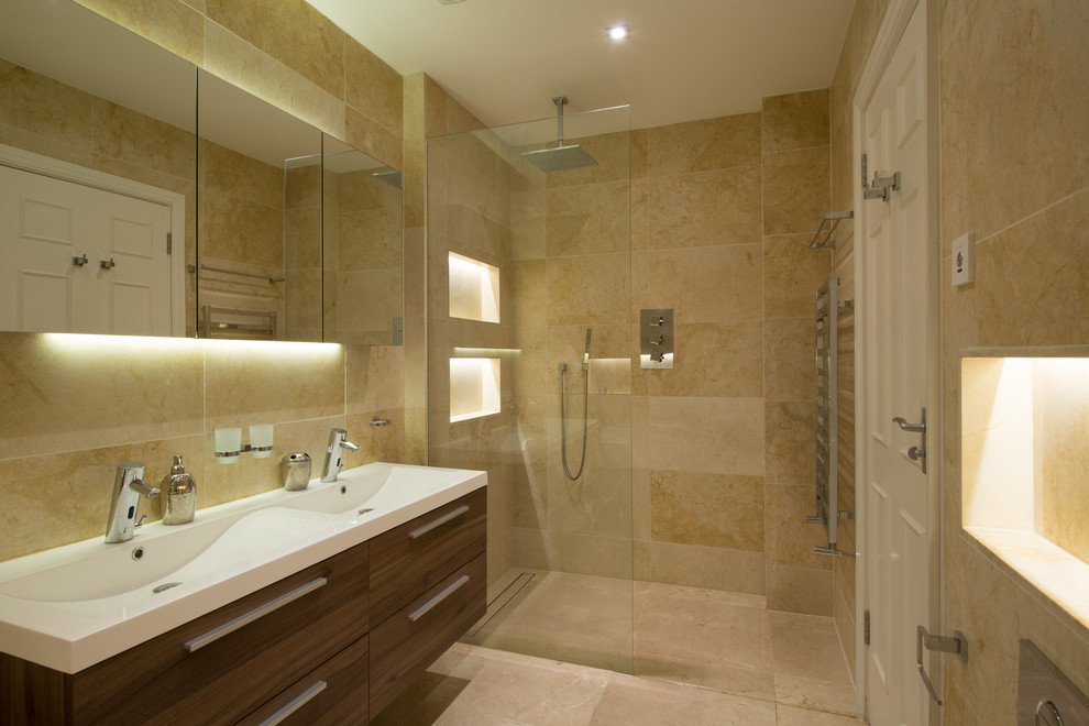 This is an example of a modern bathroom in London with furniture-like cabinets, medium wood cabinets, engineered quartz benchtops, beige tile, stone tile, an open shower, a wall-mount toilet, a wall-mount sink and limestone floors.