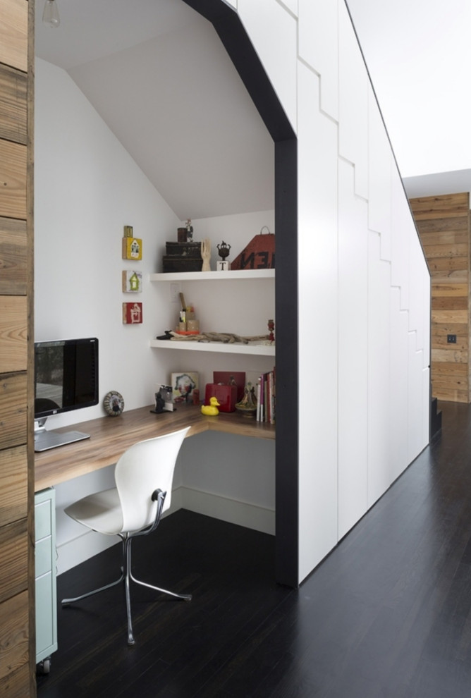 Photo of a small modern study room in Montpellier with white walls, medium hardwood floors, a built-in desk and brown floor.