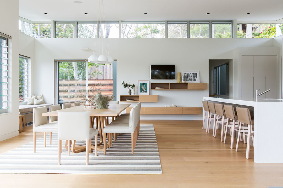 Photo of a beach style dining room in Sydney with white walls and light hardwood floors.