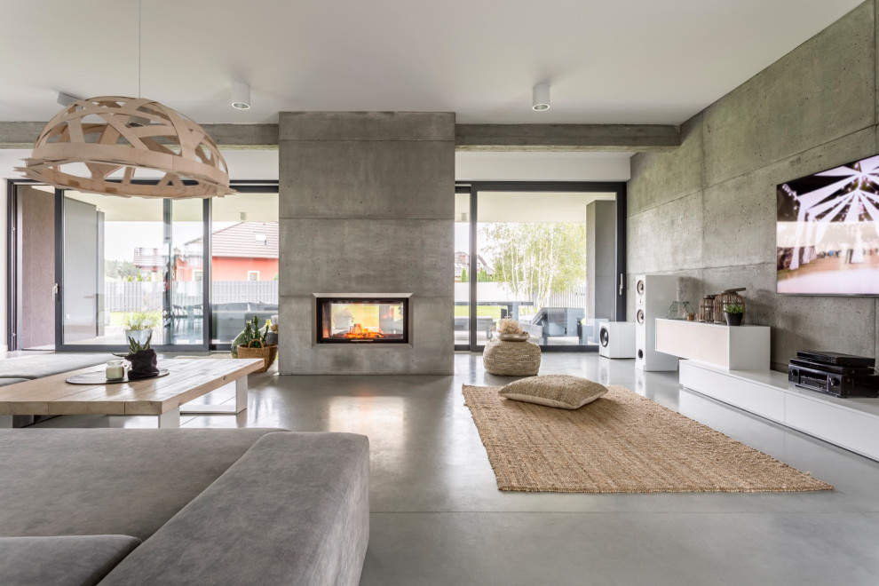 Large contemporary open concept living room in Phoenix with grey walls, concrete floors, a hanging fireplace, a concrete fireplace surround, a wall-mounted tv, grey floor, coffered and panelled walls.