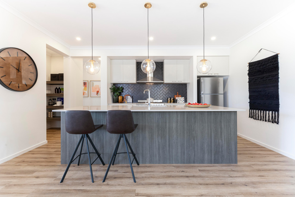 Photo of a contemporary kitchen in Melbourne with an undermount sink, grey cabinets, quartz benchtops, grey splashback, ceramic splashback, stainless steel appliances, light hardwood floors, with island, white benchtop and brown floor.