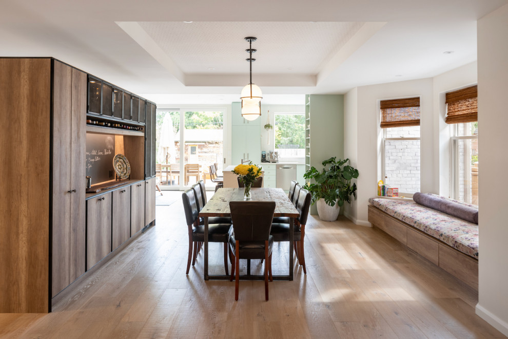Cette image montre une grande salle à manger ouverte sur la cuisine design avec un mur blanc, parquet clair, un sol marron et un plafond décaissé.
