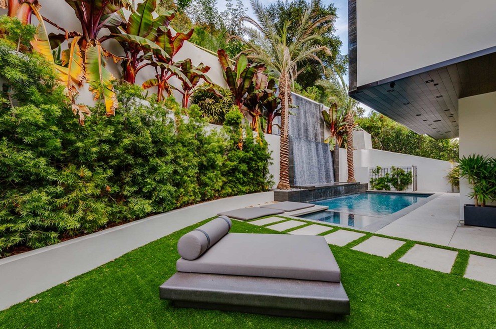 Photo of an expansive contemporary backyard pool in Los Angeles with a water feature and concrete pavers.