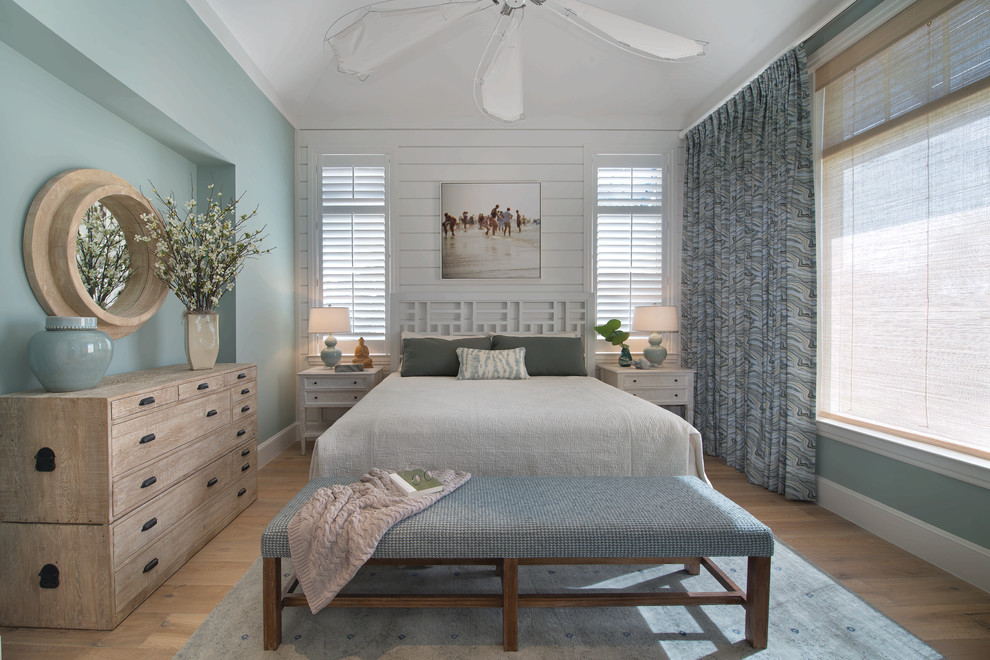 This is an example of a beach style bedroom in Miami with blue walls and light hardwood floors.
