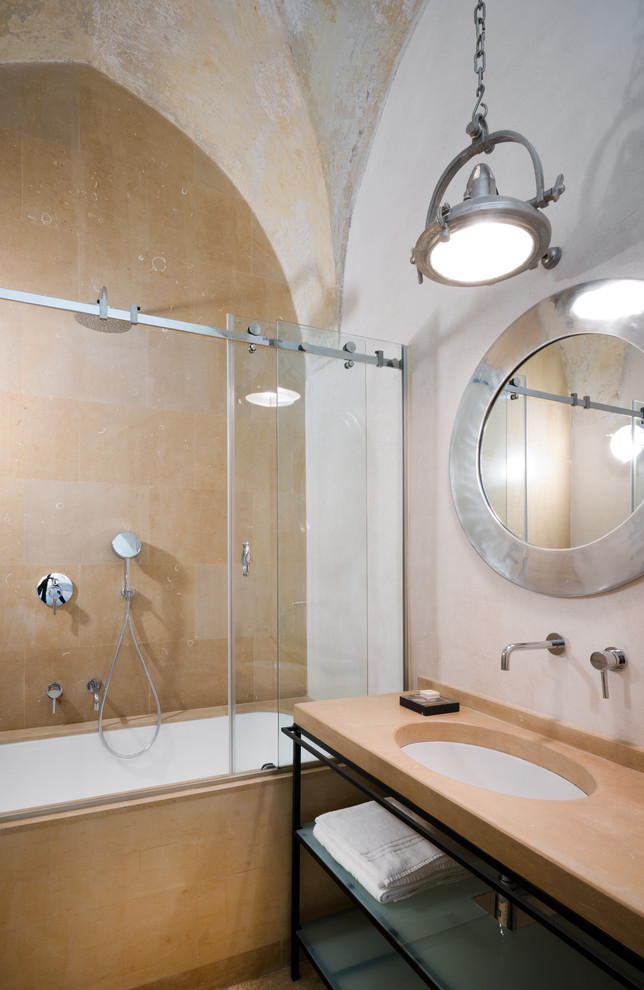 Design ideas for a mediterranean bathroom in Milan with open cabinets, an undermount tub, a shower/bathtub combo, beige tile, white walls, an undermount sink, a sliding shower screen and beige benchtops.