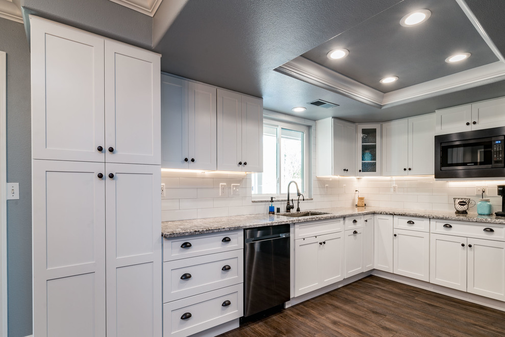 Mid-sized transitional u-shaped dark wood floor and brown floor eat-in kitchen photo with an undermount sink, shaker cabinets, white cabinets, granite countertops, white backsplash, subway tile backsplash, stainless steel appliances and no island