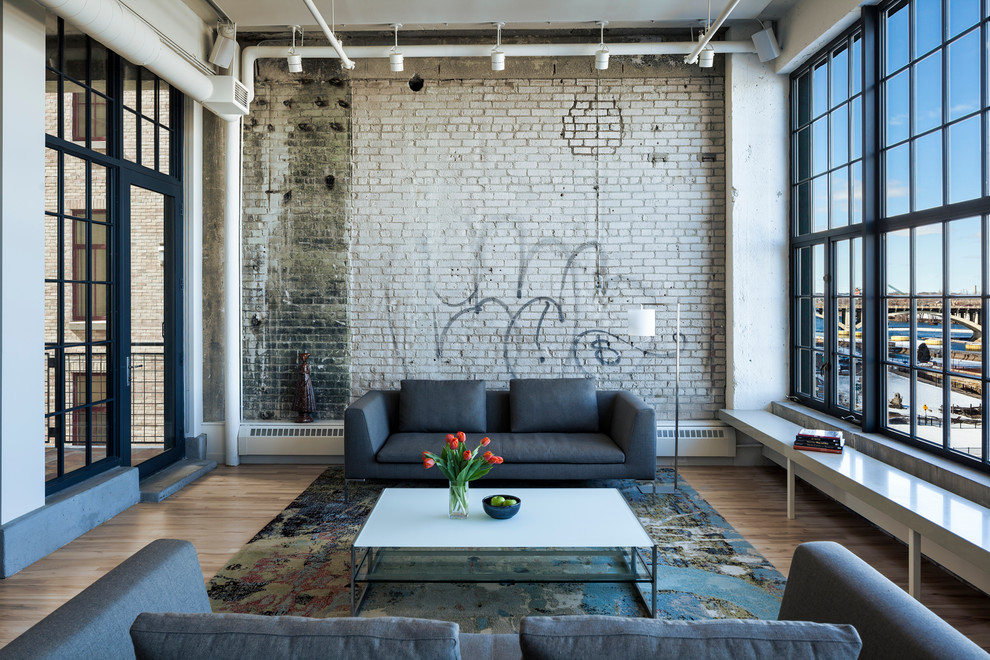 This is an example of a large industrial living room in Minneapolis with light hardwood floors.