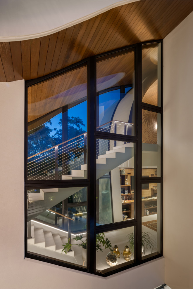 На фото: большая лестница на больцах в стиле модернизм с деревянными ступенями и перилами из смешанных материалов без подступенок