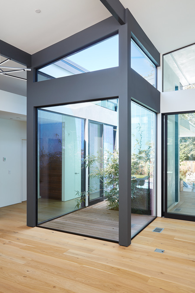 Los Altos New Residence - Klopf Architecture and Outer space Landscape Architects designed a new warm, modern, open, indoor-outdoor home in Los Altos, California. Inspired by mid-century modern homes but looking for something completely new and custom, the owners, a couple with two children, bought an older ranch style home with the intention of replacing it. 

Created on a grid, the house is designed to be at rest with differentiated spaces for activities; living, playing, cooking, dining and a piano space. The low-sloping gable roof over the great room brings a grand feeling to the space. The clerestory windows at the high sloping roof make the grand space light and airy. 
Upon entering the house, an open atrium entry in the middle of the house provides light and nature to the great room. The Heath tile wall at the back of the atrium blocks direct view of the rear yard from the entry door for privacy. 
The bedrooms, bathrooms, play room and the sitting room are under flat wing-like roofs that balance on either side of the low sloping gable roof of the main space. Large sliding glass panels and pocketing glass doors foster openness to the front and back yards. In the front there is a fenced-in play space connected to the play room, creating an indoor-outdoor play space that could change in use over the years. The play room can also be closed off from the great room with a large pocketing door. In the rear, everything opens up to a deck overlooking a pool where the family can come together outdoors.
Wood siding travels from exterior to interior, accentuating the indoor-outdoor nature of the house. Where the exterior siding doesn’t come inside, a palette of white oak floors, white walls, walnut cabinetry, and dark window frames ties all the spaces together to create a uniform feeling and flow throughout the house. The custom cabinetry matches the minimal joinery of the rest of the house, a trim-less, minimal appearance. Wood siding was mitered in the corners, including where siding meets the interior drywall. Wall materials were held up off the floor with a minimal reveal. This tight detailing gives a sense of cleanliness to the house. 
The garage door of the house is completely flush and of the same material as the garage wall, de-emphasizing the garage door and making the street presentation of the house kinder to the neighborhood.
The house is akin to a custom, modern-day Eichler home in many ways. Inspired by mid-century modern homes with today’s materials, approaches, standards, and technologies. The goals were to create an indoor-outdoor home that was energy-efficient, light and flexible for young children to grow. This 3,000 square foot, 3 bedroom, 2.5 bathroom new house is located in Los Altos in the heart of the Silicon Valley. 


Klopf Architecture Project Team: John Klopf, AIA, and Chuang-Ming Liu
 Landscape Architect: Outer space Landscape Architects
 Structural Engineer: ZFA Structural Engineers
 Staging: Da Lusso Design 
 Photography ©2018 Mariko Reed
 Location: Los Altos, CA 
Year completed: 2017