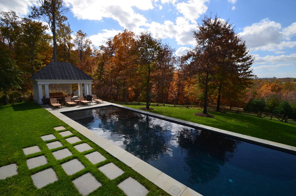 Design ideas for a large country backyard rectangular lap pool in DC Metro with natural stone pavers.