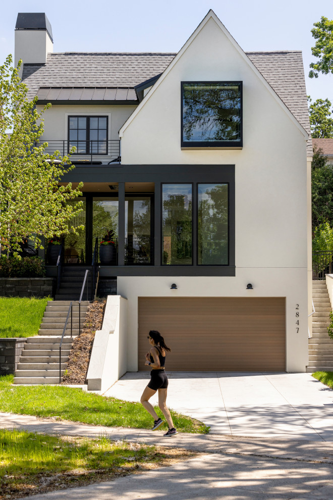 Large transitional three-storey stucco white house exterior in Minneapolis with a mixed roof and a grey roof.
