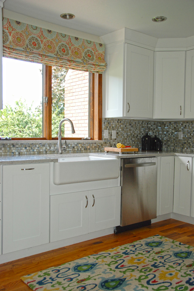 Photo of a small beach style u-shaped separate kitchen in Omaha with shaker cabinets, white cabinets, quartz benchtops, a peninsula, grey benchtop, a farmhouse sink, multi-coloured splashback, glass tile splashback, stainless steel appliances, medium hardwood floors and orange floor.