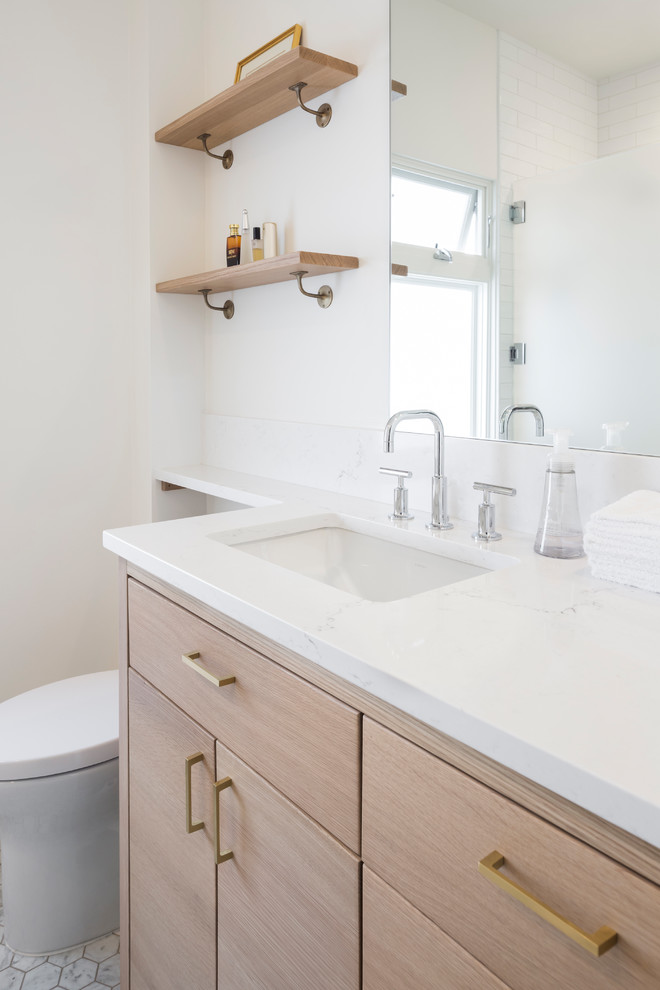 Inspiration for a small scandinavian master bathroom in Seattle with flat-panel cabinets, light wood cabinets, an alcove tub, a shower/bathtub combo, a one-piece toilet, white tile, ceramic tile, white walls, marble floors, an undermount sink, engineered quartz benchtops, white floor and a hinged shower door.