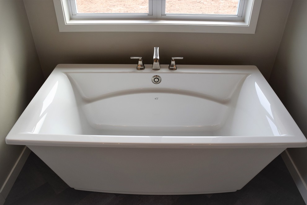 Freestanding bathtub - mid-sized master ceramic tile freestanding bathtub idea with recessed-panel cabinets, white cabinets, a two-piece toilet, beige walls, a drop-in sink and laminate countertops