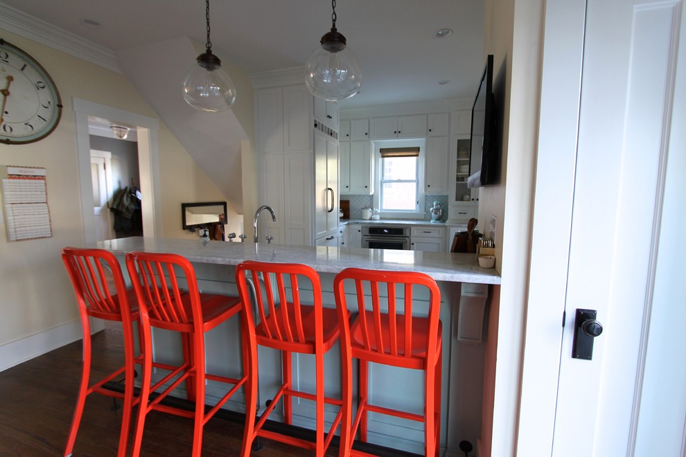 Kitchen - transitional medium tone wood floor kitchen idea in Omaha with a farmhouse sink, shaker cabinets, white cabinets, quartzite countertops, white backsplash, ceramic backsplash, stainless steel appliances and a peninsula